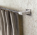 Tringle à anneaux , tube en aluminium chromé avec support corner en aluminium mat, un rideaux gris à tête simple est suspendu à la tringle.